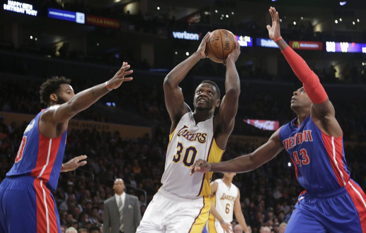 Lakers power forward Julius Randle cuts through the defense of Pistons center Andre Drummond, left, and forward Anthony Tolliver during a Nov. 15 game at Staples Center.