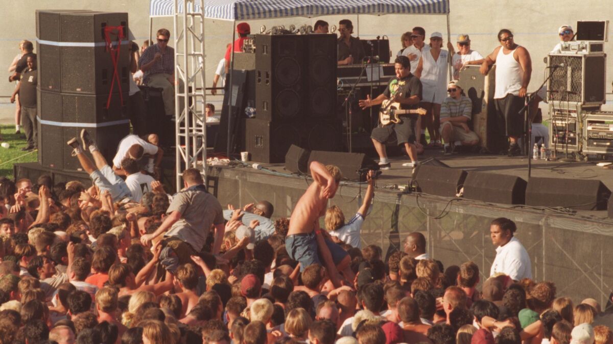 Bodies surf above the crowd as NOFX performs at the Warped Tour in the Olympic Velodrome at Cal State Dominguez Hills on July 7, 1996.