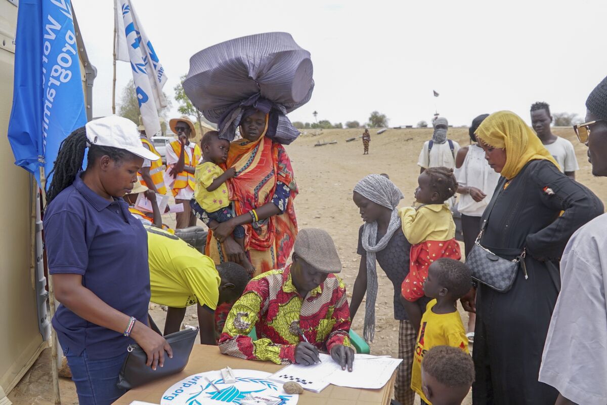 Women and children line up to register at the table.