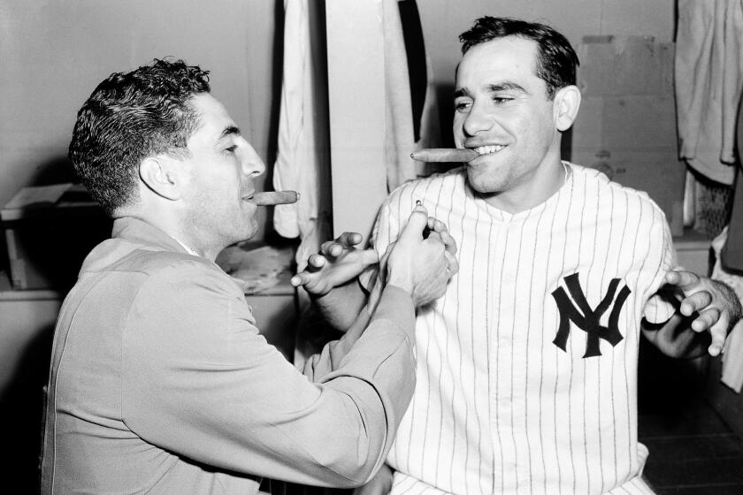Yankees shortstop Phil Rizzuto, left, celebrates with teammate Yogi Berra after the birth of the catcher's son.
