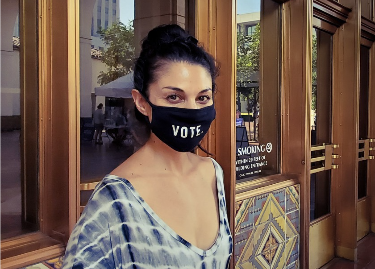 A woman wears a black mask with the word vote