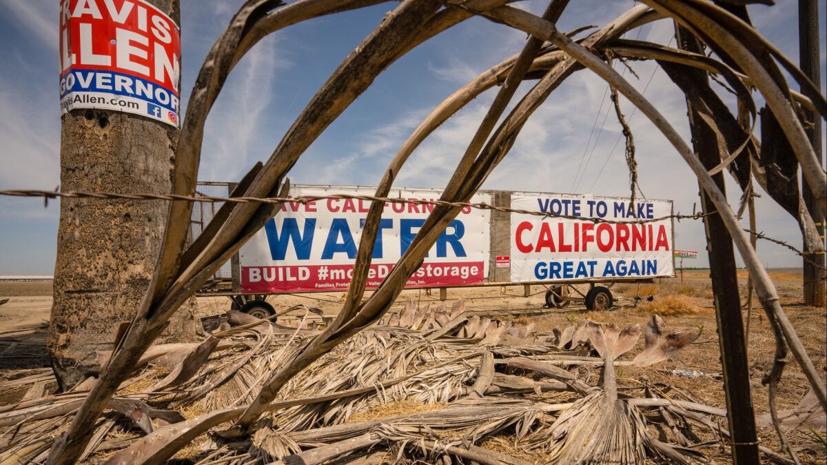 An adapted Trump slogan sign and a sign representing farmers' water needs sit alongside a highway in Hanford, Calif. on May 20.