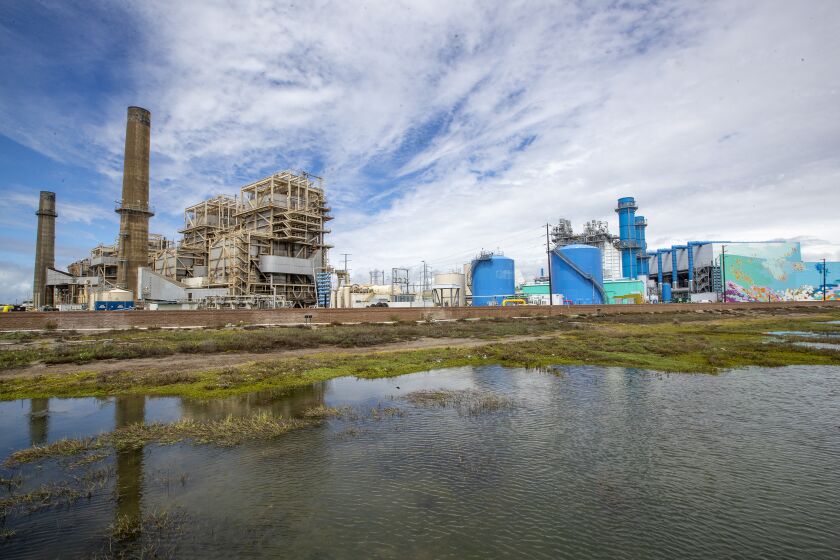 Huntington Beach, CA - March 28: An old AES power plant, which is still partially in use, stands beside a new natural gas-powered power plant and wetlands in Huntington Beach. Poseidon Water has proposed to build a large desalination plant on a portion of the site and would use an existing ocean water intake pipe in Huntington Beach, CA Monday, March 28, 2022. Opponents say the water is too costly, energy-intensive, bad for the environment and not needed because the Orange County Water District has a large groundwater basin that is fortified with rainwater from storm runoff, Santa Ana River water, and the nation's largest wastewater-to-groundwater system. (Allen J. Schaben / Los Angeles Times)