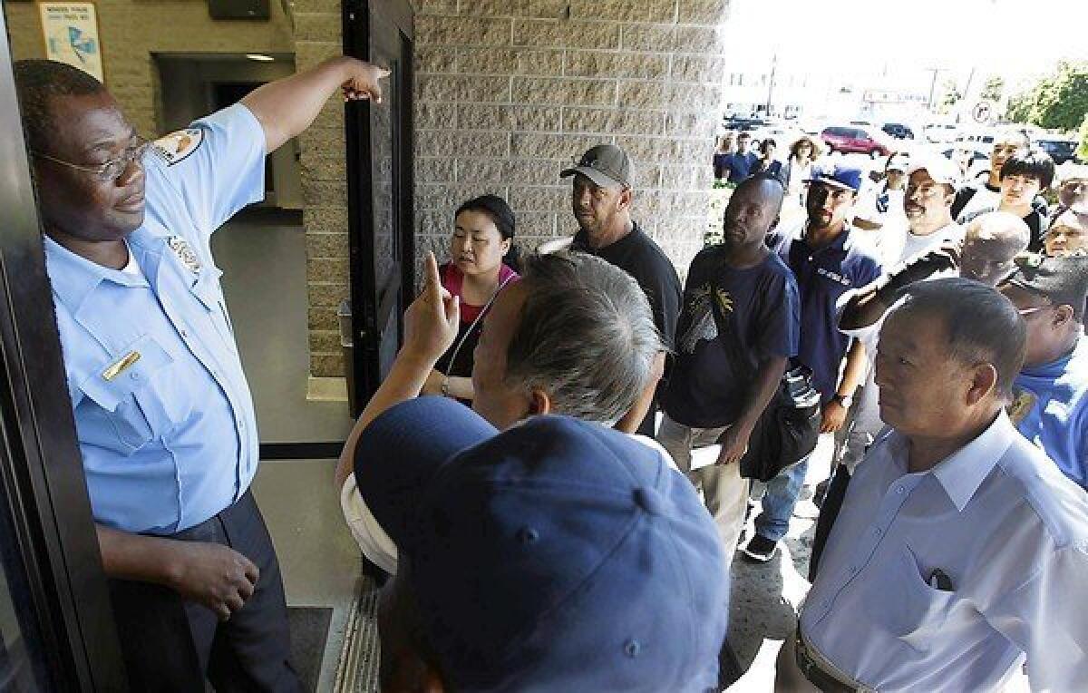 A security guard directs people to the end of a long line outside the DMV office in South Los Angeles on Tuesday. A computer crash at DMV offices statewide left clerks without access to information needed for issuing licenses and vehicle registrations.