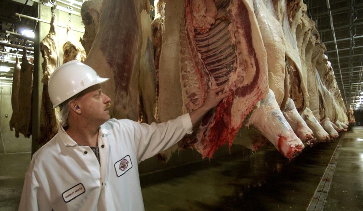 A slaughter manager looks over sides of beef hanging in a cooling room at the Creekstone Farm Premium Beef meatpacking plant in Arkansas City, Kan. A side of beef, a dog, a ski trip and plastic surgery are among the most unusual expense report requests , according to a study.