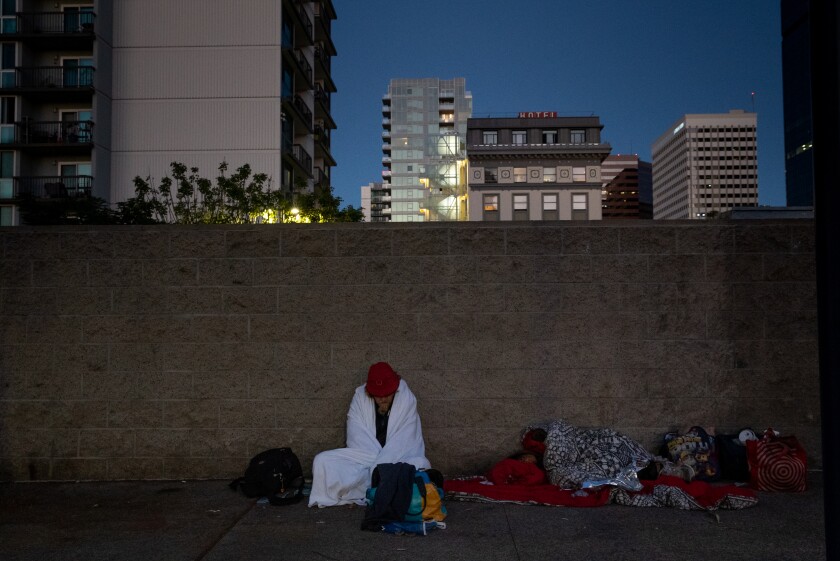 People experiencing homelessness try to stay warm as the sun begins to rise after being awoken.