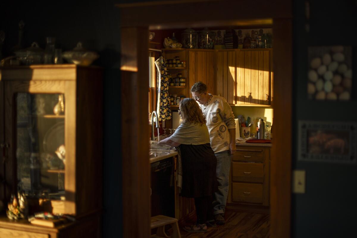 Two women stand at a kitchen sink 