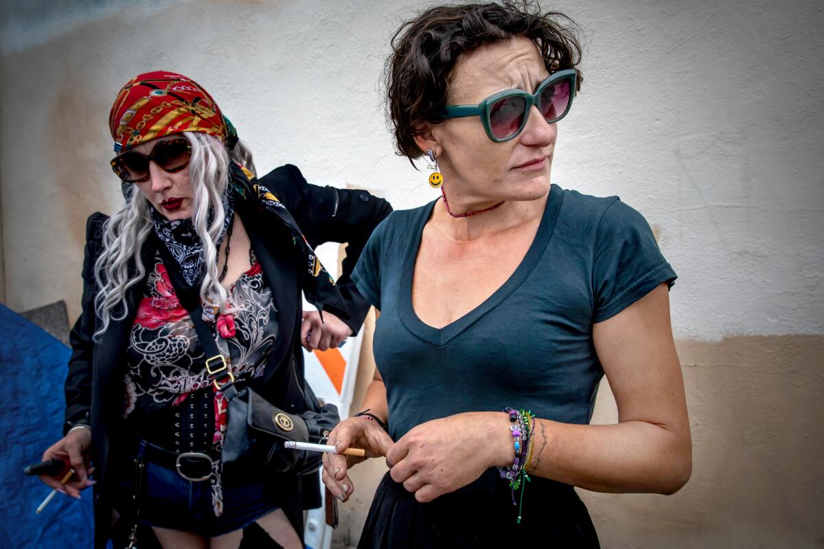 Two woman, one wearing a bandana, hold cigarettes.