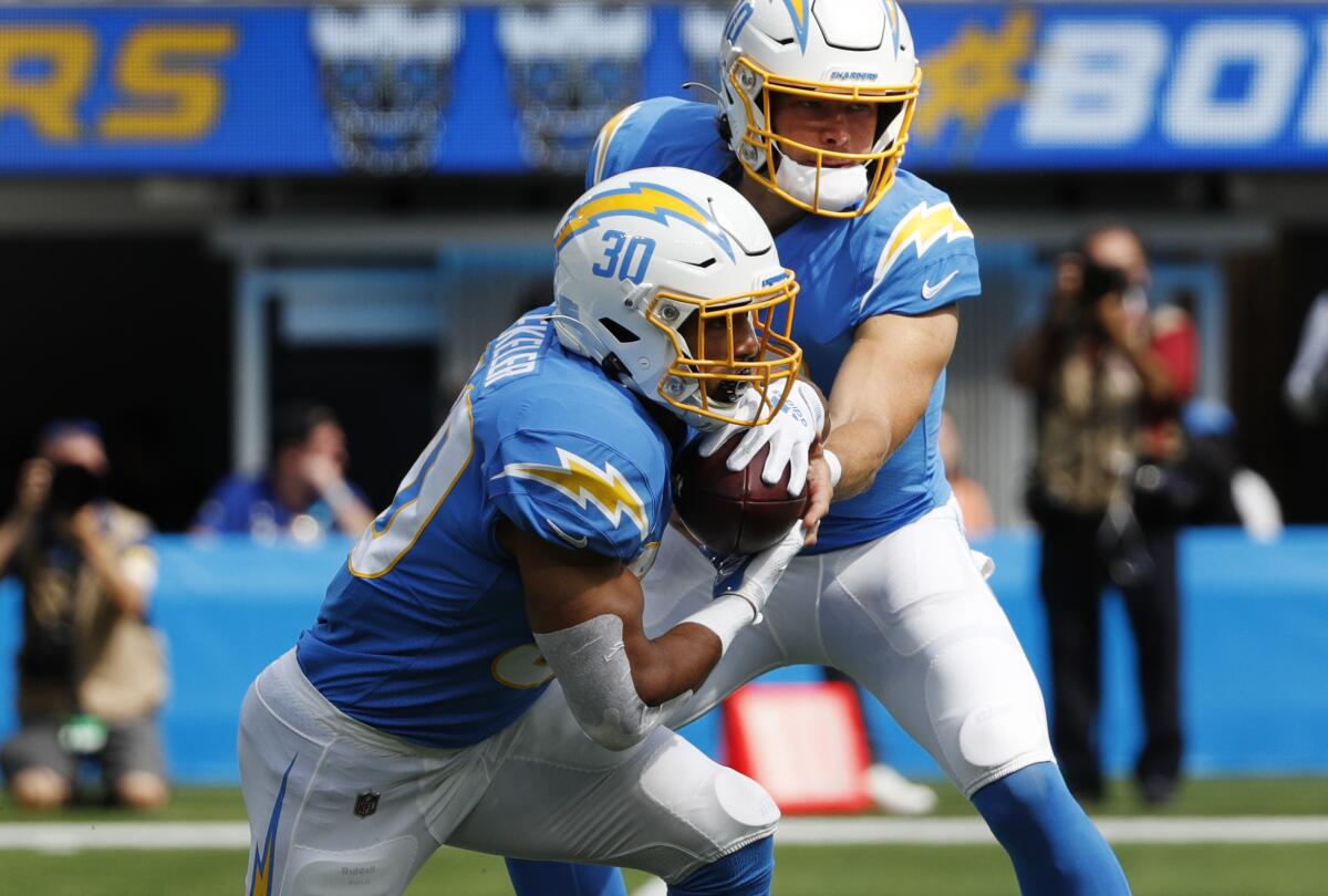 Chargers quarterback Justin Herbert (10) hands off to running back Austin Ekeler against the Cleveland Browns.