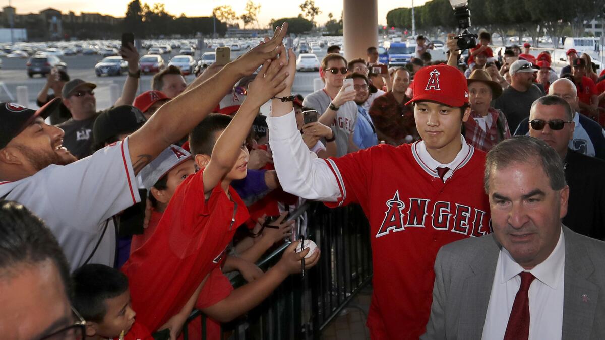 Shohei Ohtani high-fives fans after his introductory news conference at Angel Stadium on Saturday.