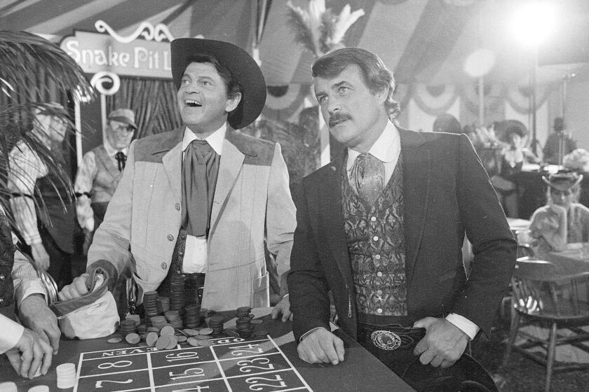 FILE - In this June 4, 1980, file photo, actors Ross Martin, left, and Robert Conrad, right, are shown while filming a scene of the motion picture "More Wild, Wild West," in Los Angeles. Conrad, the rugged, contentious actor who starred in the hugely popular 1960s television series "Hawaiian Eye" and "The Wild, Wild West," has died at age 84. A family spokesperson says the actor died Saturday morning, Feb. 8, 2020, in Malibu, Calif., from heart failure. (AP Photo/Wally Fong, File)