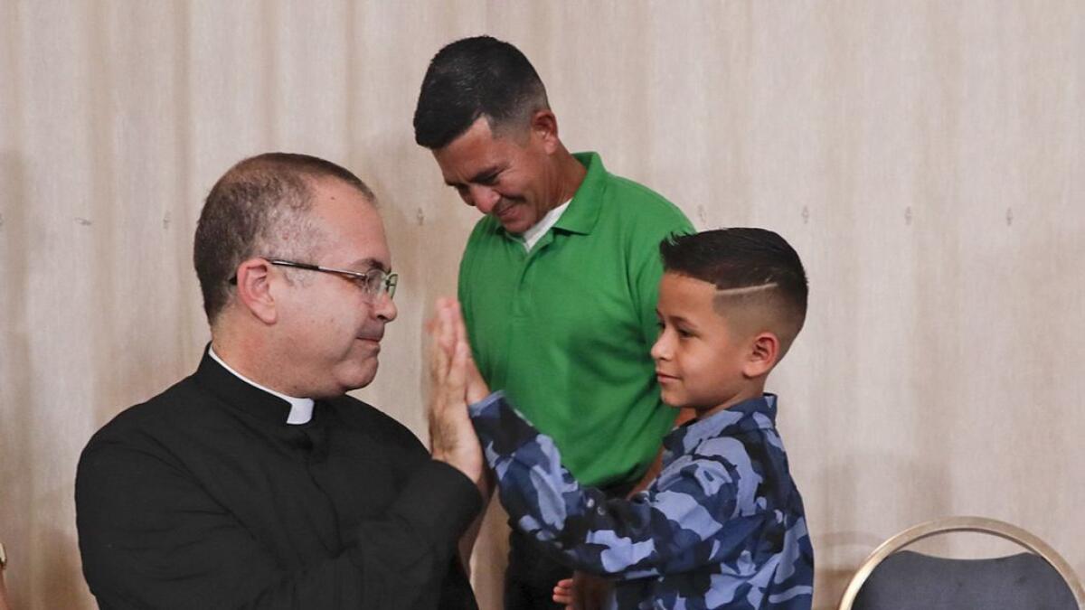 Omar Marino Dominguez Mejia looks on as the Rev. Jorge Gomez greets his son, Arin.
