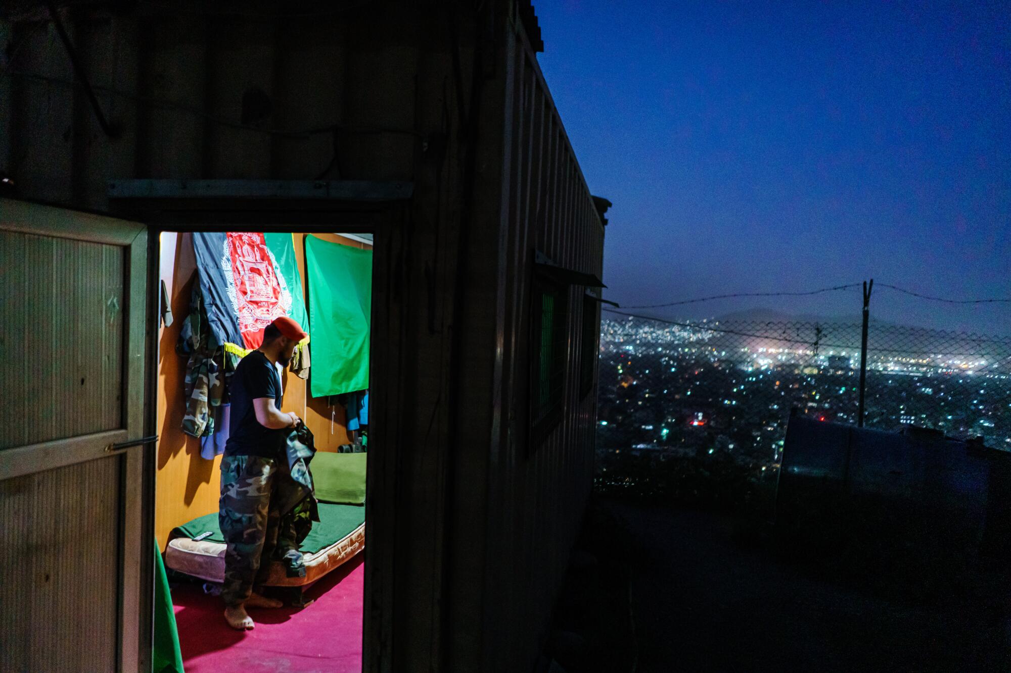 An Afghan soldier looks at city below from his home