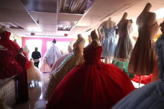 A woman stands in a front of a window near quinceanera dresses