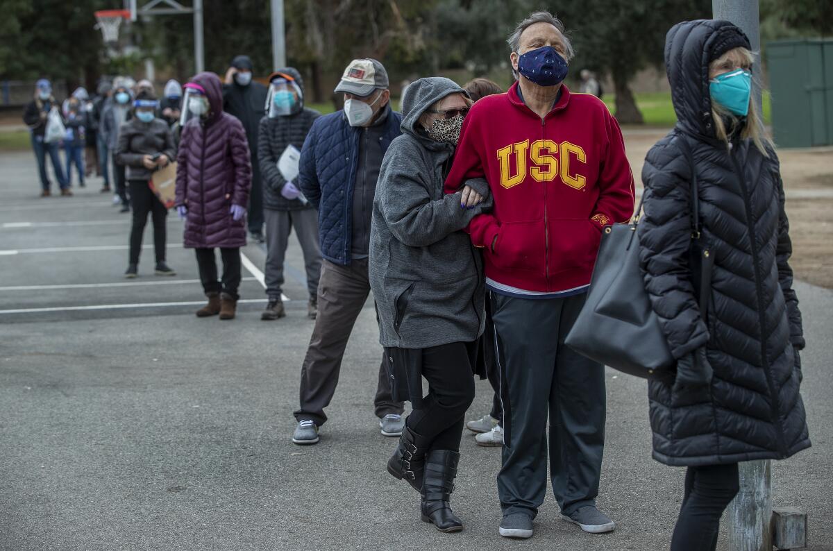 People, many of them seniors, wait in line for a COVID-19 vaccine.