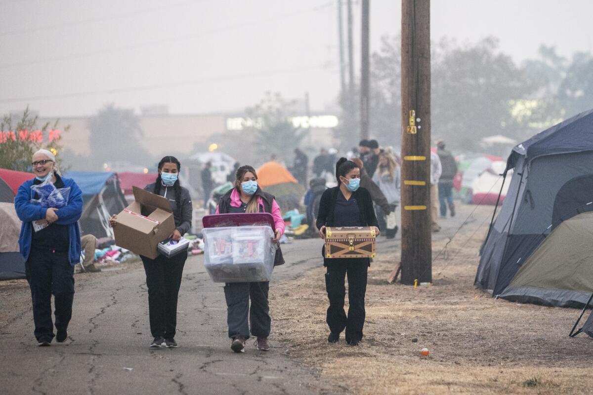 Volunteers hand out supplies at an encampment of people who were displaced by the Camp fire.