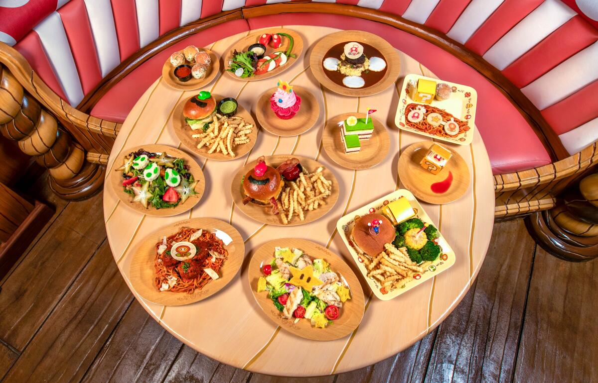 Plates of burgers and fries, salads, cupcakes and other dishes on a wooden table