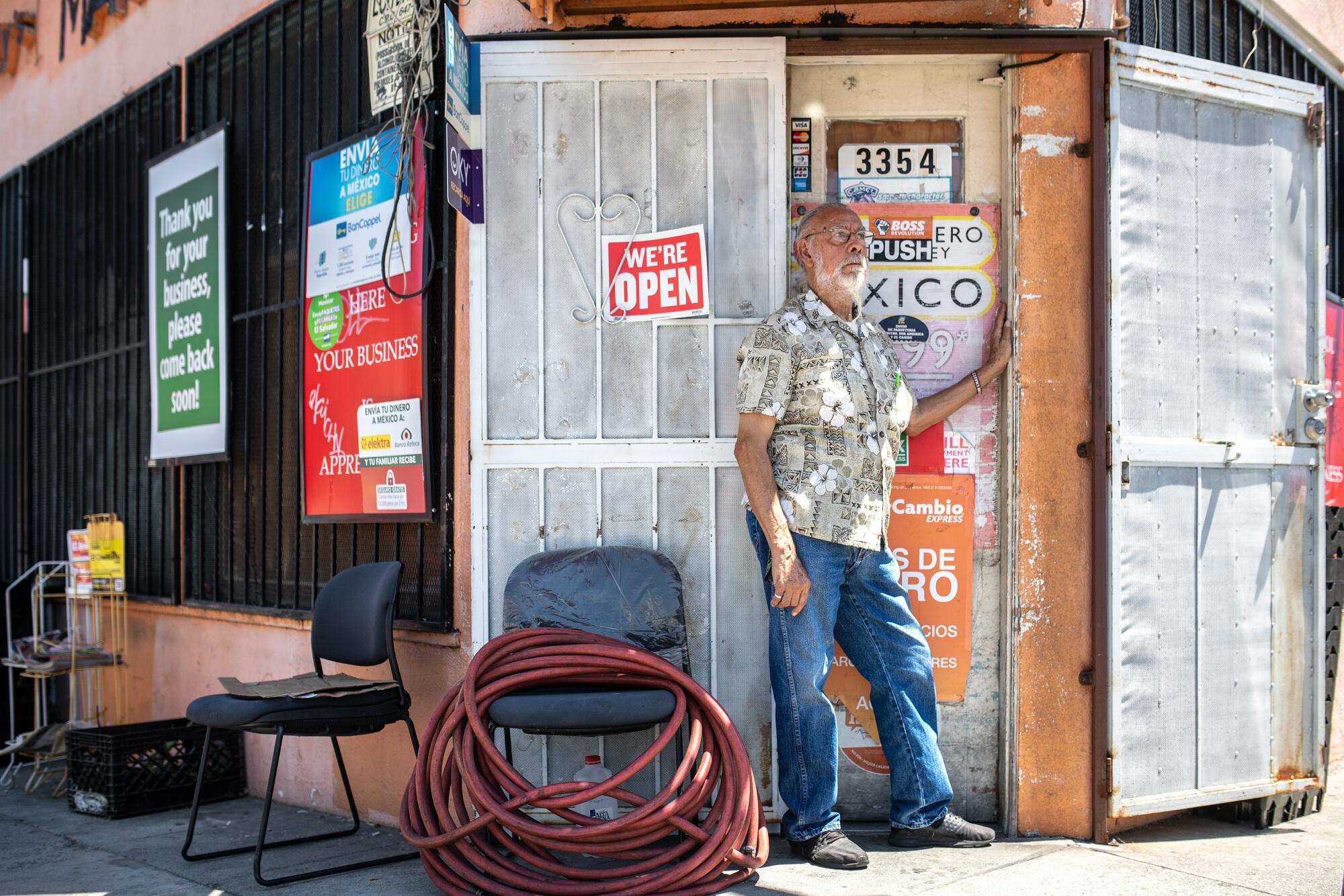 A man stands in front of a store with a "We're open" sign on its door.