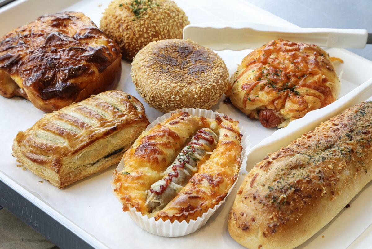 Among the savory baked items at 85°C are (clockwise from top left): the vegan potato croquette; vegan curry bun; cheese dog; garlic bread; sausage roll; kale danish; and ham and cheese pastry. 