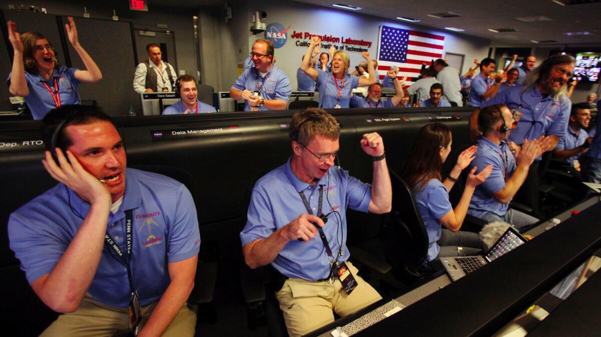 Pasadena, CA, United States: Sunday, August 5, 2012 ? Peter Ilott, center, and his colleagues celebrate a successful landing inside the Spaceflight Operations Facility for NASA's Mars Science Laboratory Curiosity rover at Jet Propulsion Laboratory (JPL) in Pasadena, California, USA on Sunday, August 5, 2012. The Curiosity robot is equipped with a nuclear?powered lab capable of vaporizing rocks and ingesting soil, measuring habitability, and potentially paving the way for human exploration. (Brian van der Brug/Los Angeles Times?POOL)