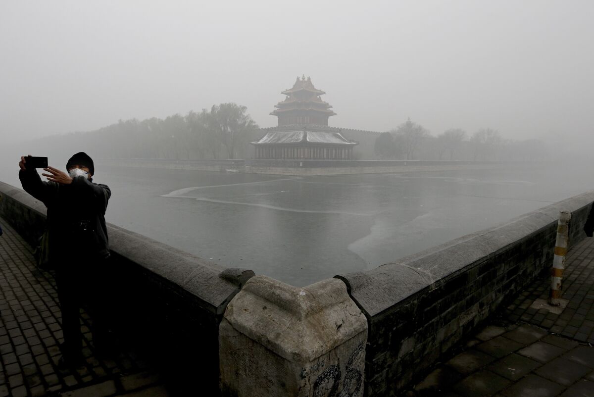A man wearing a mask to protect himself from pollutants takes a selfie on a heavily polluted day in Beijing. 