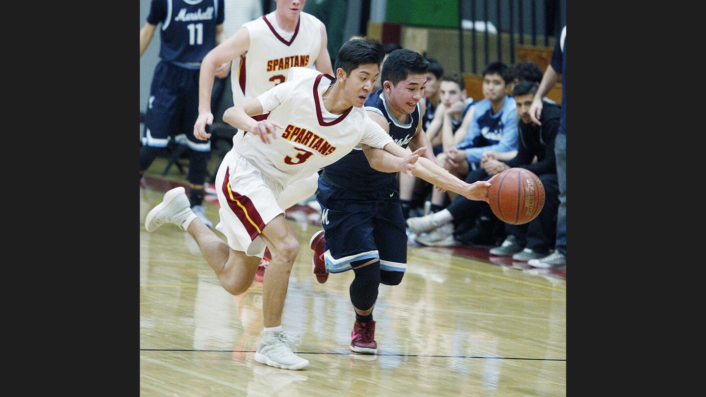 La Canada's Noah Ford steals the ball from Marshall's Karl Go in a nonleague boys' basketball game at La Canada High School on Tuesday, December 12, 2017.