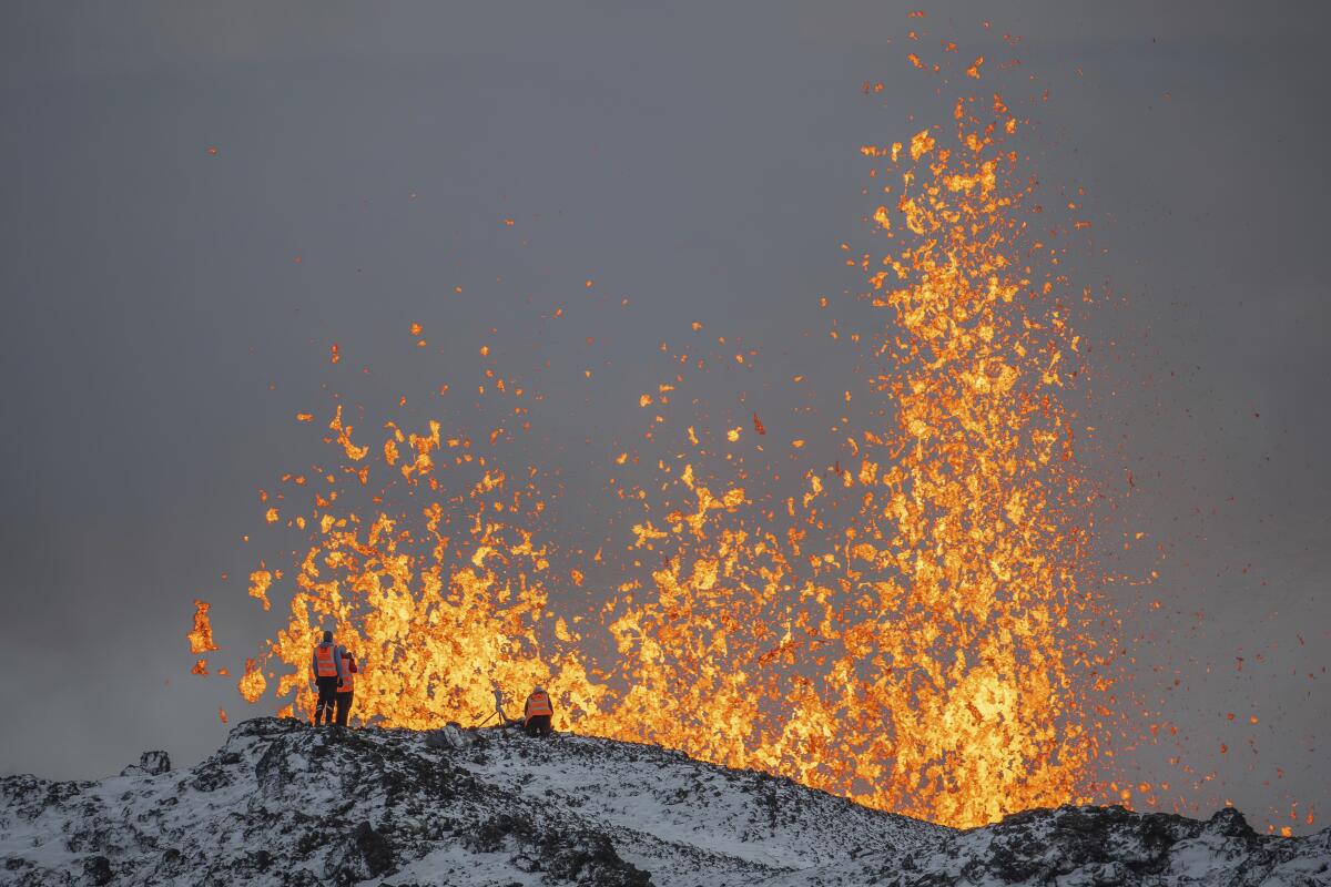 People standing on the ridge of an eruptive fissure of an active volcano in Iceland.