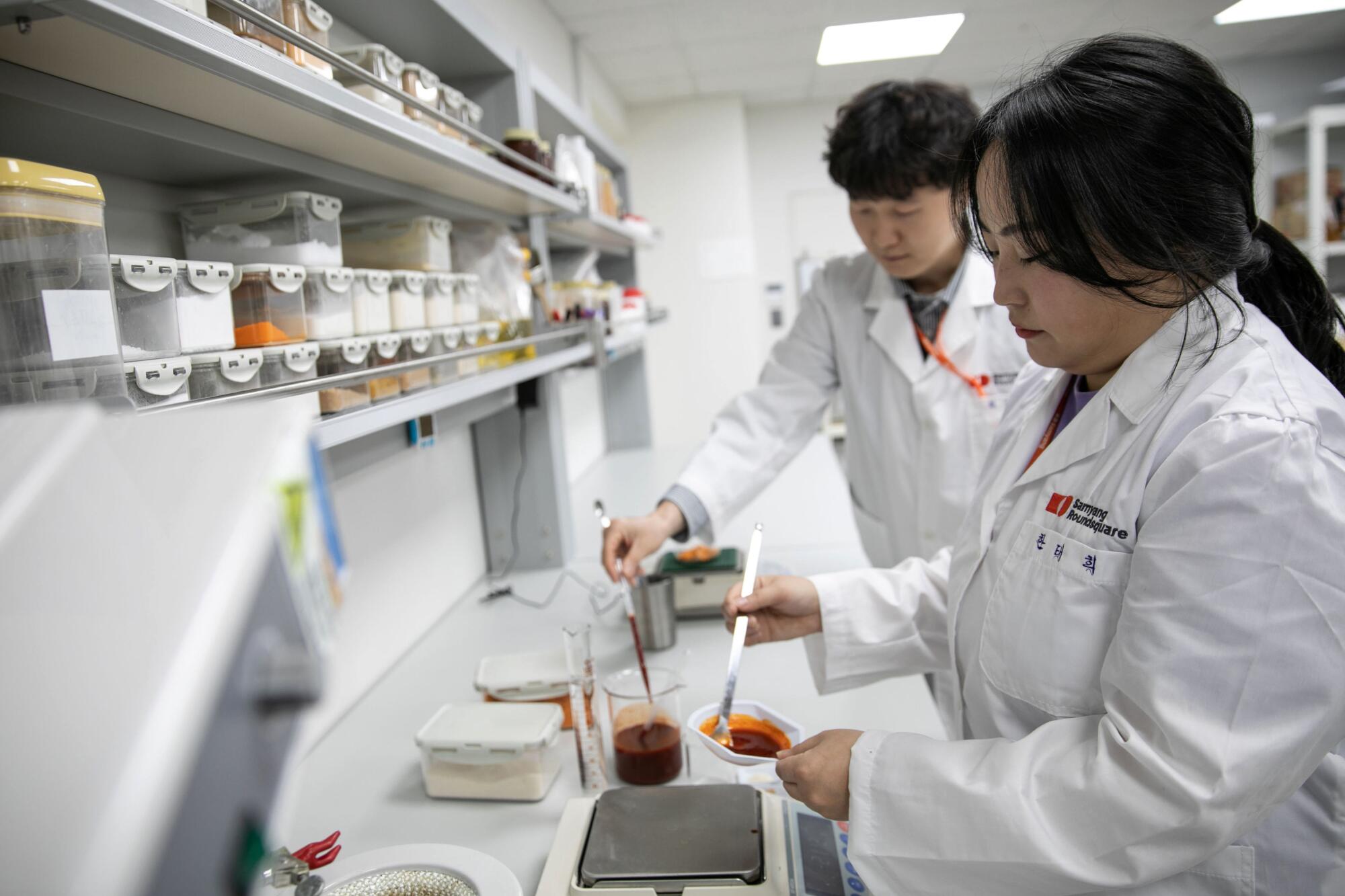 Food scientists weigh the ramen sauce in the food laboratory inside the headquarters
