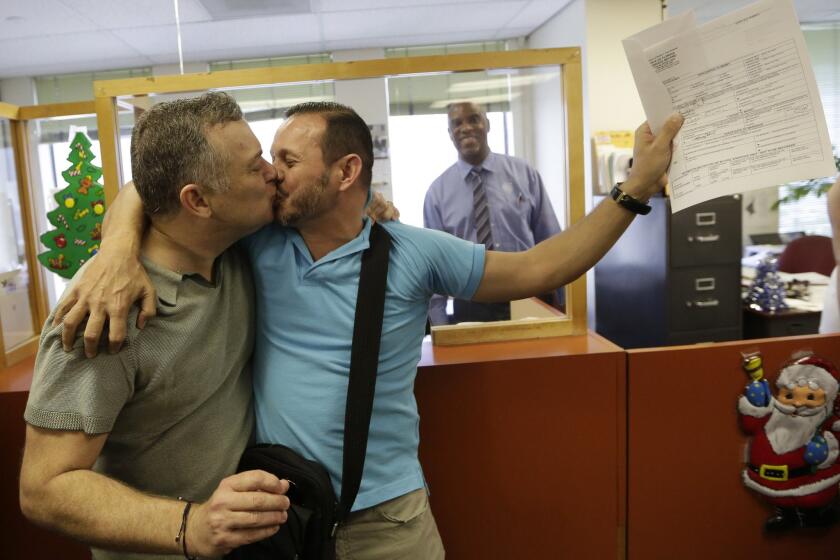 Jeff Ronci, left, kisses his partner of 15 years, Juan Talavera, as they hold up their marriage license at the Miami-Dade County clerk of courts office.