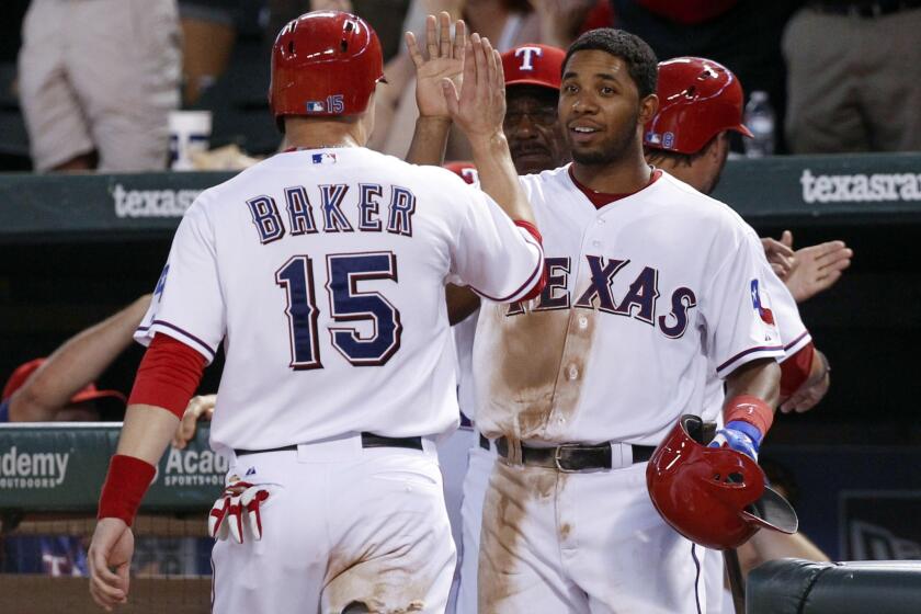 Jeff Baker, left, is congratulated by Texas Rangers teammate Elvis Andrus after scoring a run during the Angels' 14-11 loss on Tuesday.