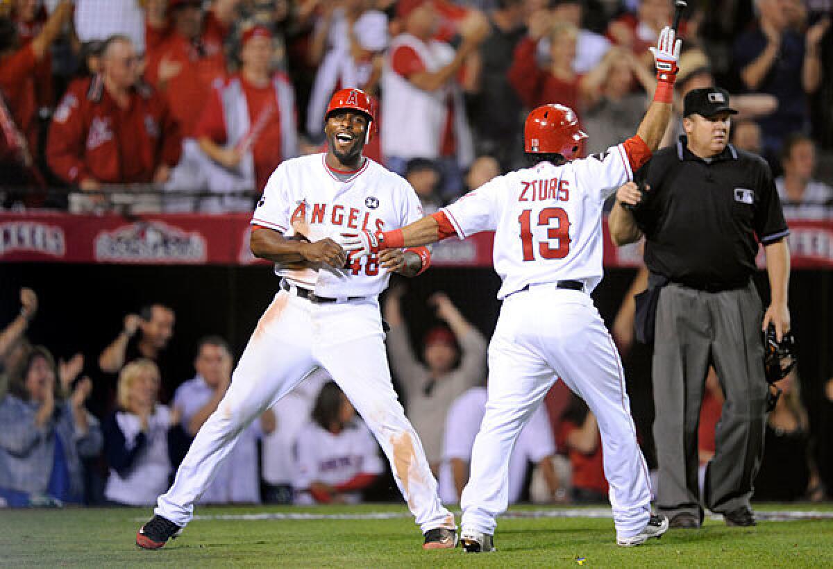 Angels center fielder Torii Hunter, left, celebrates with second baseman Maicer Izturis after scoring the go-ahead run against the Yankees in the seventh inning of Game 5 of the American League Championship Series on Thursday night at Angel Stadium.