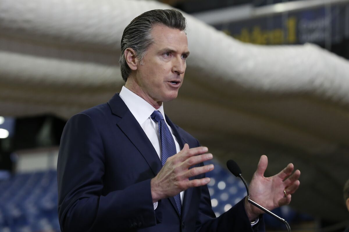 Gov. Gavin Newsom discusses the acquisition of the Sleep Train Arena in Sacramento for use as a field hospital in this April 6 Associated Press photo.