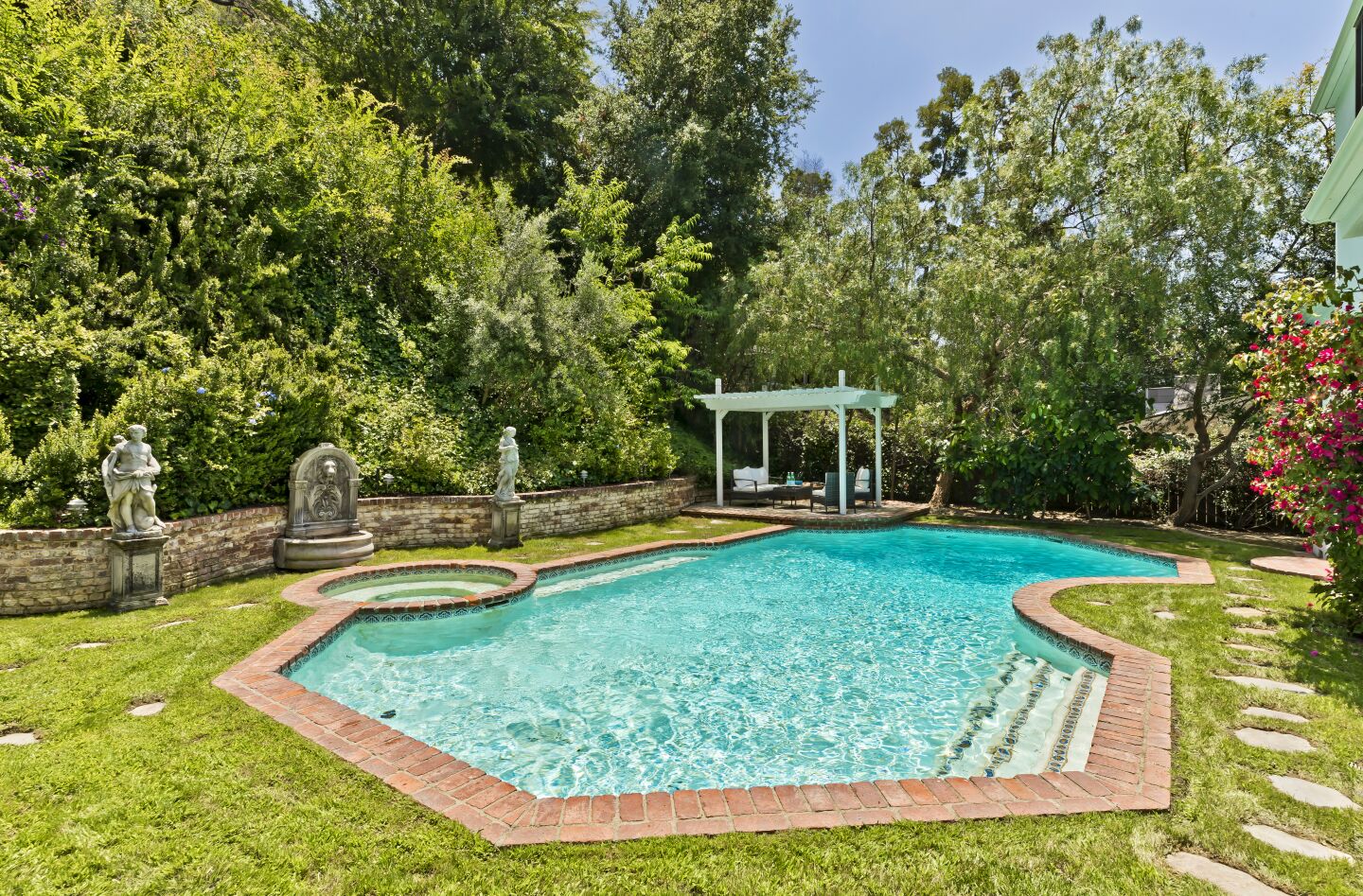 Brickwork surrounds a saltwater pool and spa in the backyard.
