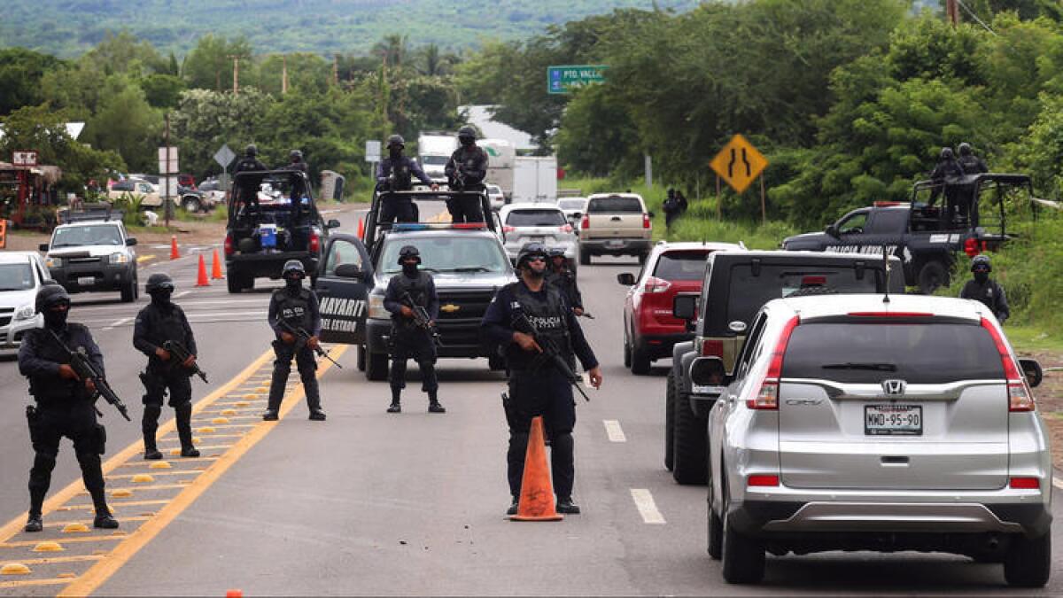 Oficiales de policía hacen guardia en un puesto de control cerca de Nayarit, México, este miércoles, luego del secuestro de un hijo del “Chapo” Guzmán, líder del cártel de Sinaloa.