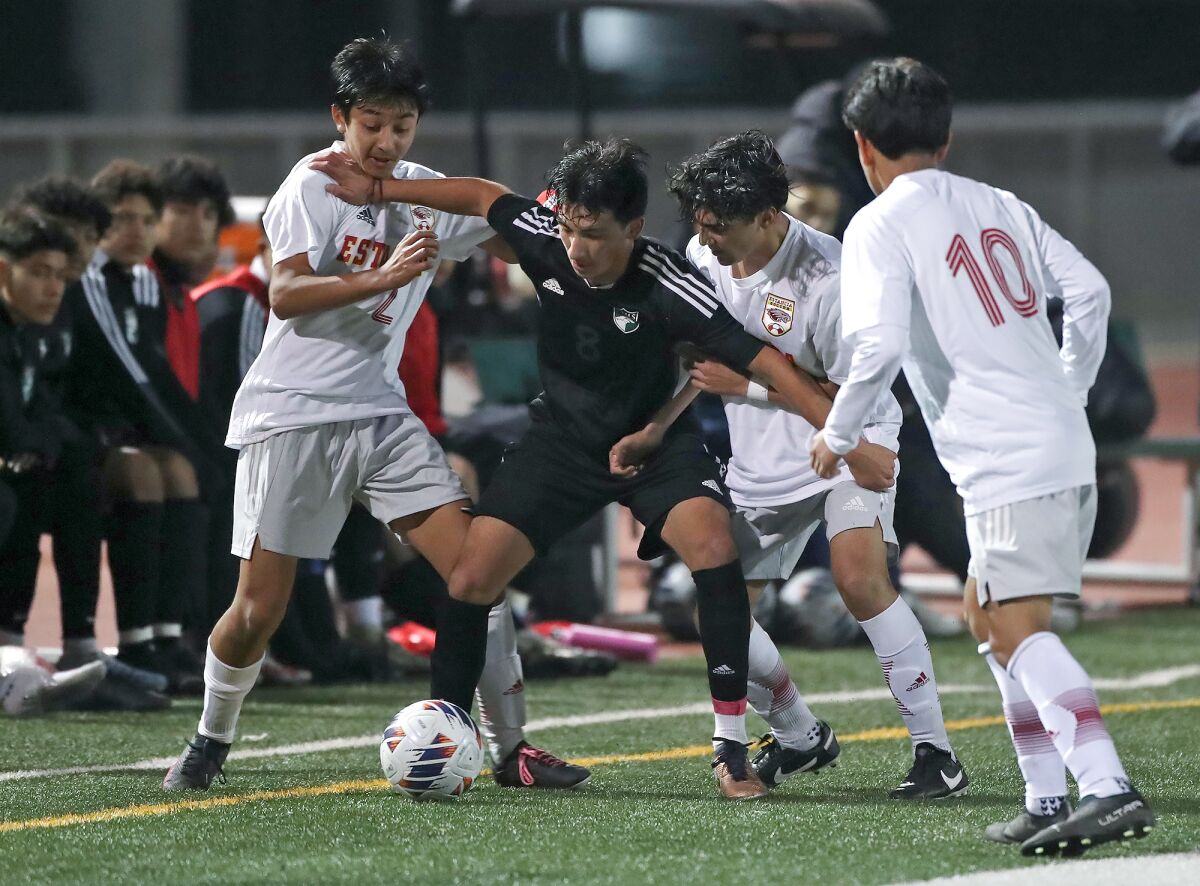 Costa Mesa's Isaiah Ponce fends off two Estancia attackers to gain possession of the ball on Friday.