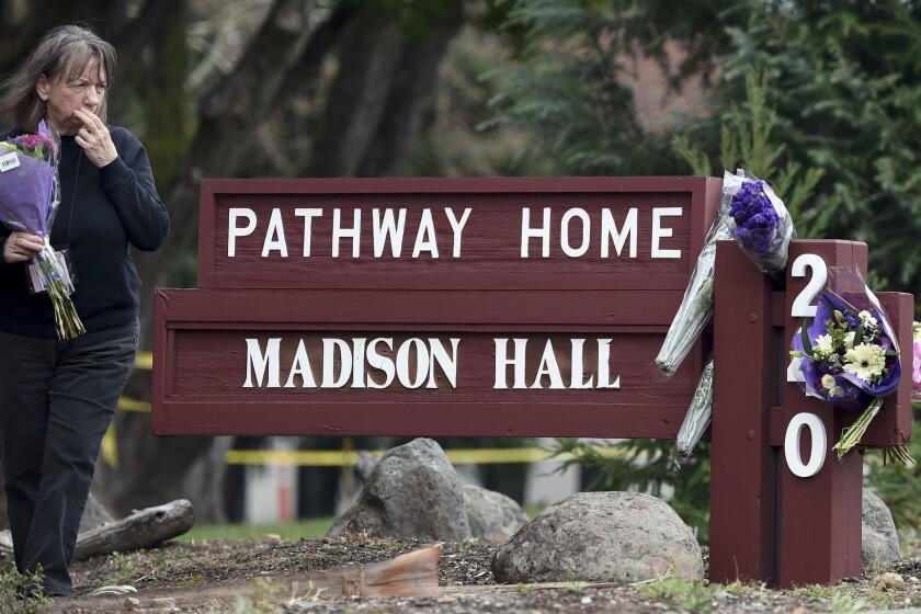 A woman who declined to give her name reacts while placing flowers at a sign where a hostage situation with an active shooter came to a tragic end the night before at the Veterans Home of California in Yountville, Calif. on Saturday, March 10, 2018. Four people were killed, including the shooter. (AP Photo/Josh Edelson)