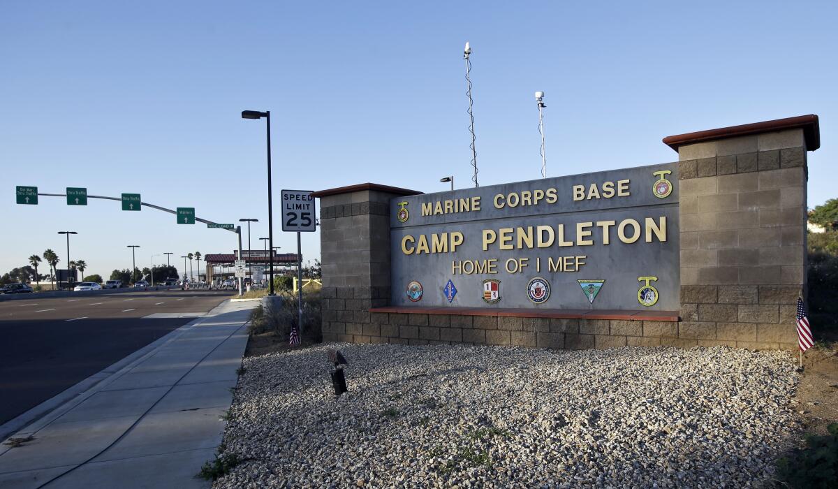 A sign for Marine Corps Base Camp Pendleton next to a road leading to the main gate
