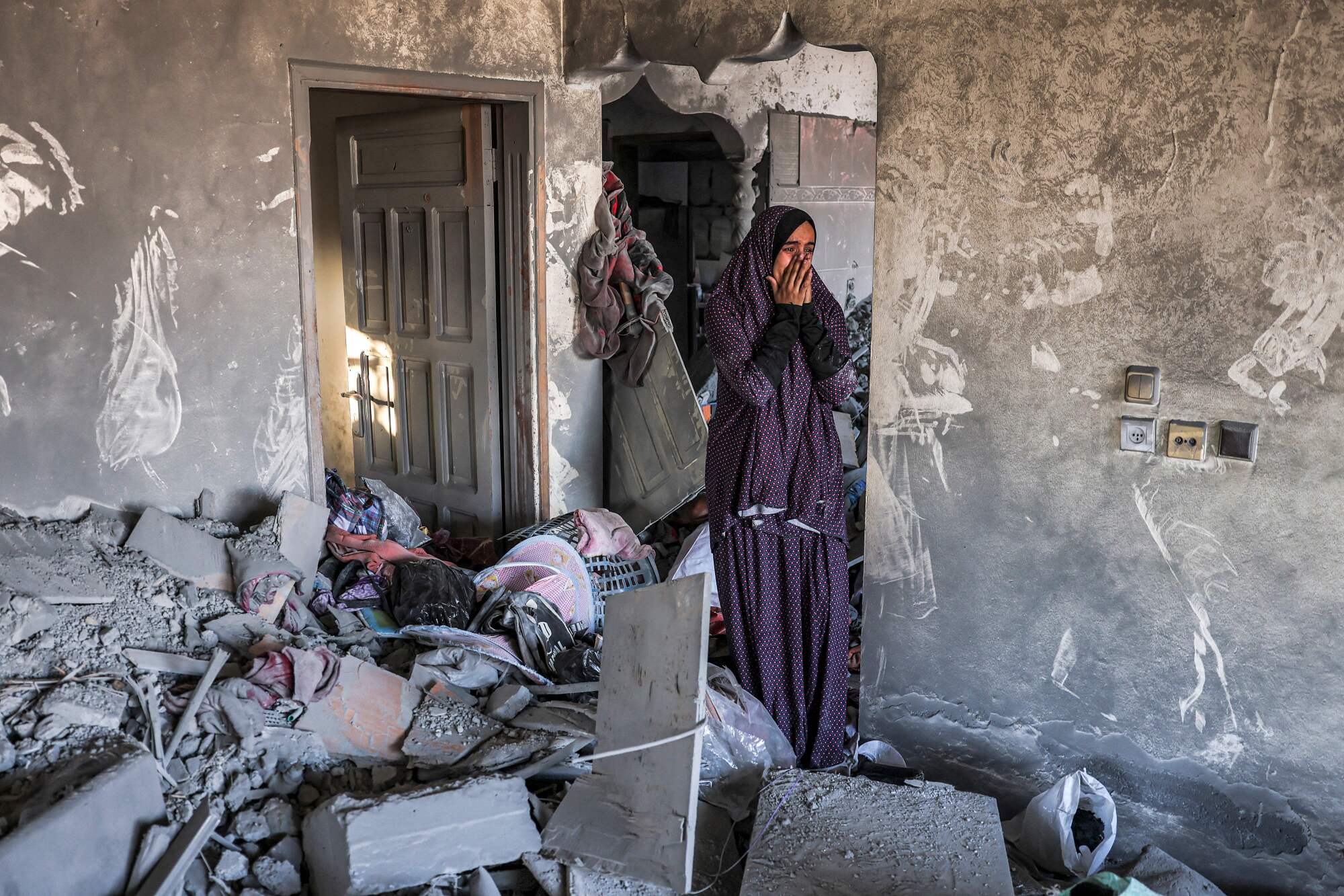 A woman in a long robe standing next to debris. 