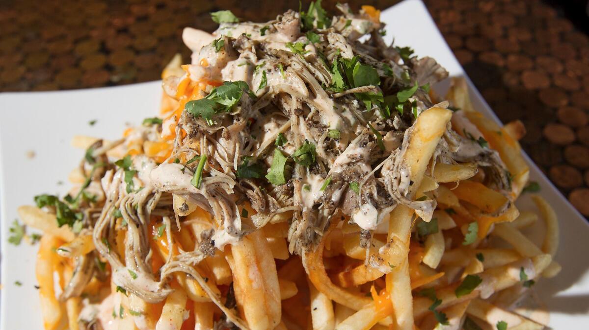The Beach Barrel's Spicy Jerk Chicken Fries are toped with melted cheese and garnished with cilantro.