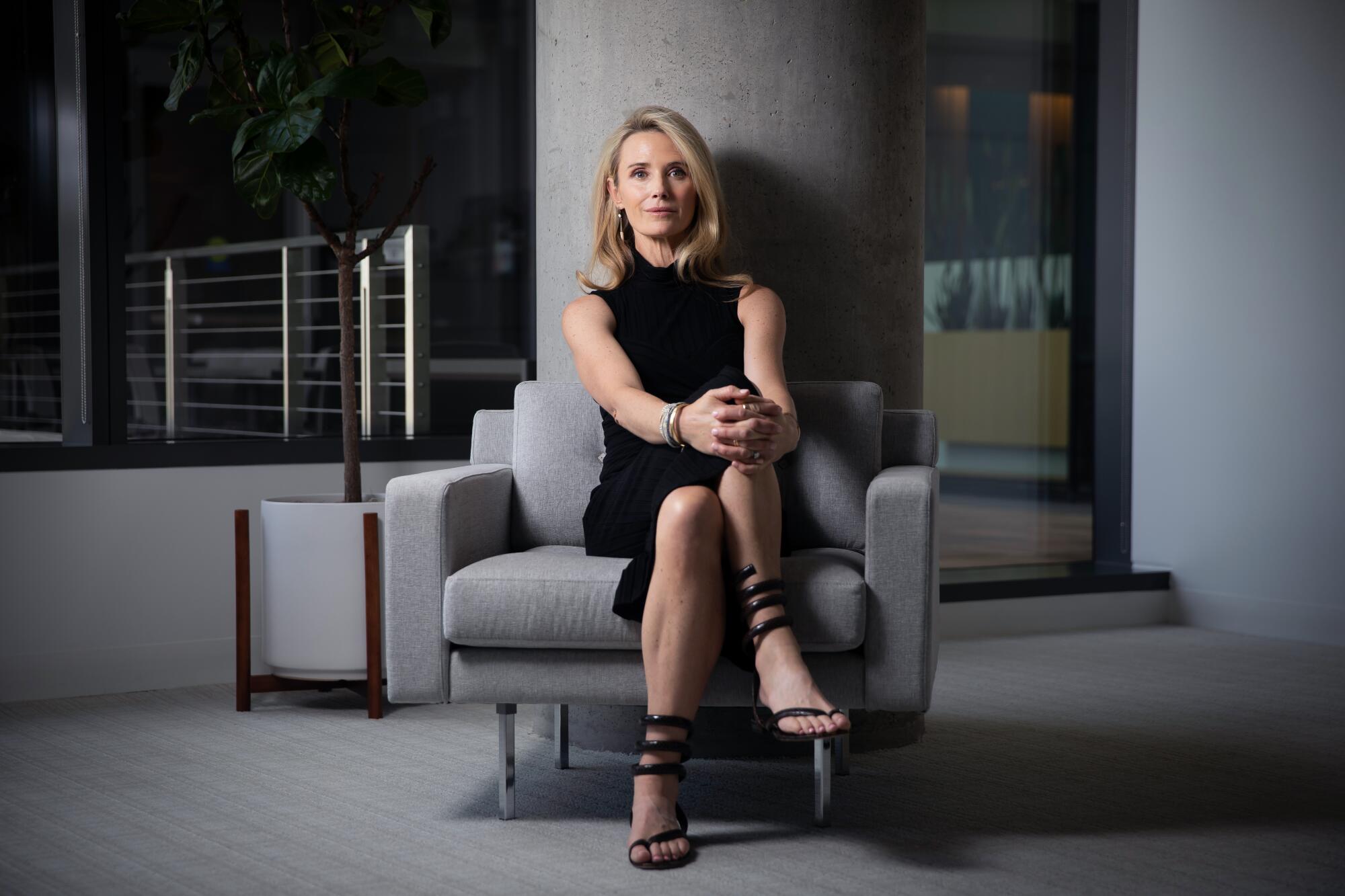 Jennifer Siebel Newsom sitting with legs crossed, hands on one knee, in a gray room