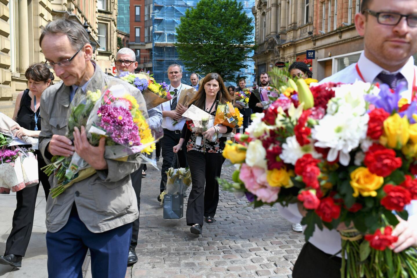 Manchester City Council workers move the floral tributes from Albert Square to St Ann's Square on Wednesday.