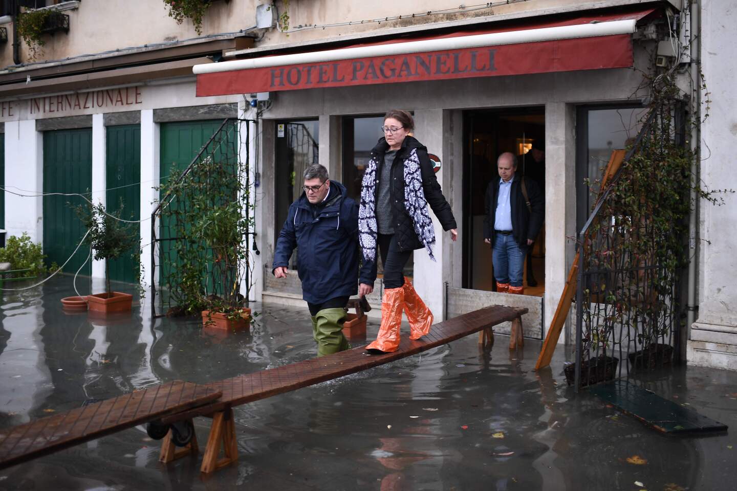 People use a makeshift footbridge to exit a flooded hotel.