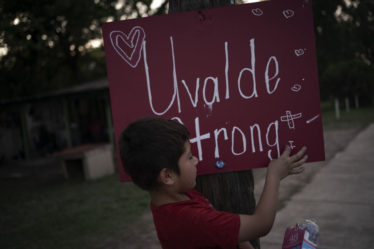 FILE - Eight-year-old Jeremiah Lennon picks at a sign that reads "Uvalde Strong" which he helped decorate and stuck on an electric pole in front of his home on May 28, 2022, in Uvalde, Texas. Lennon was in a classroom just next to the room where three of his friends were slain when a gunman killed 19 students and two teachers at Robb Elementary. (AP Photo/Wong Maye-E, File)