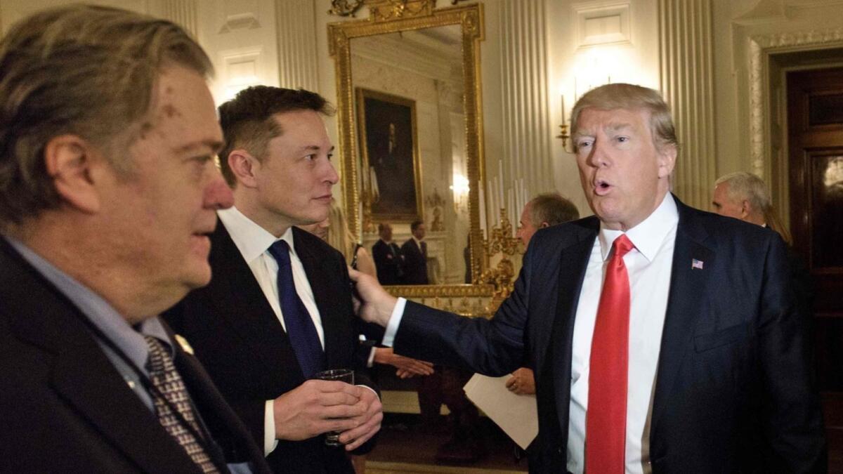 President Trump greets Elon Musk, center, at a policy forum at the White House in February 2017. At left is Steve Bannon, then a White House advisor.