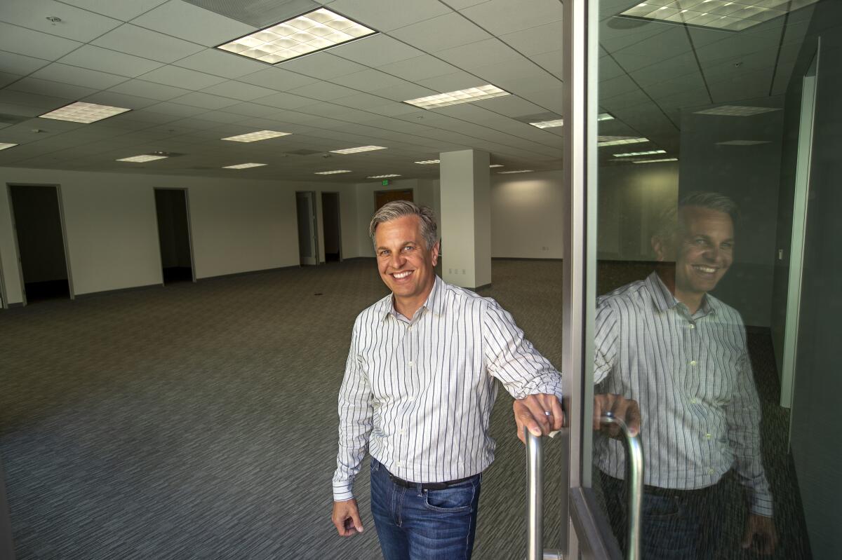 Real estate broker Greg Lovett in an empty office with his reflection to the right.