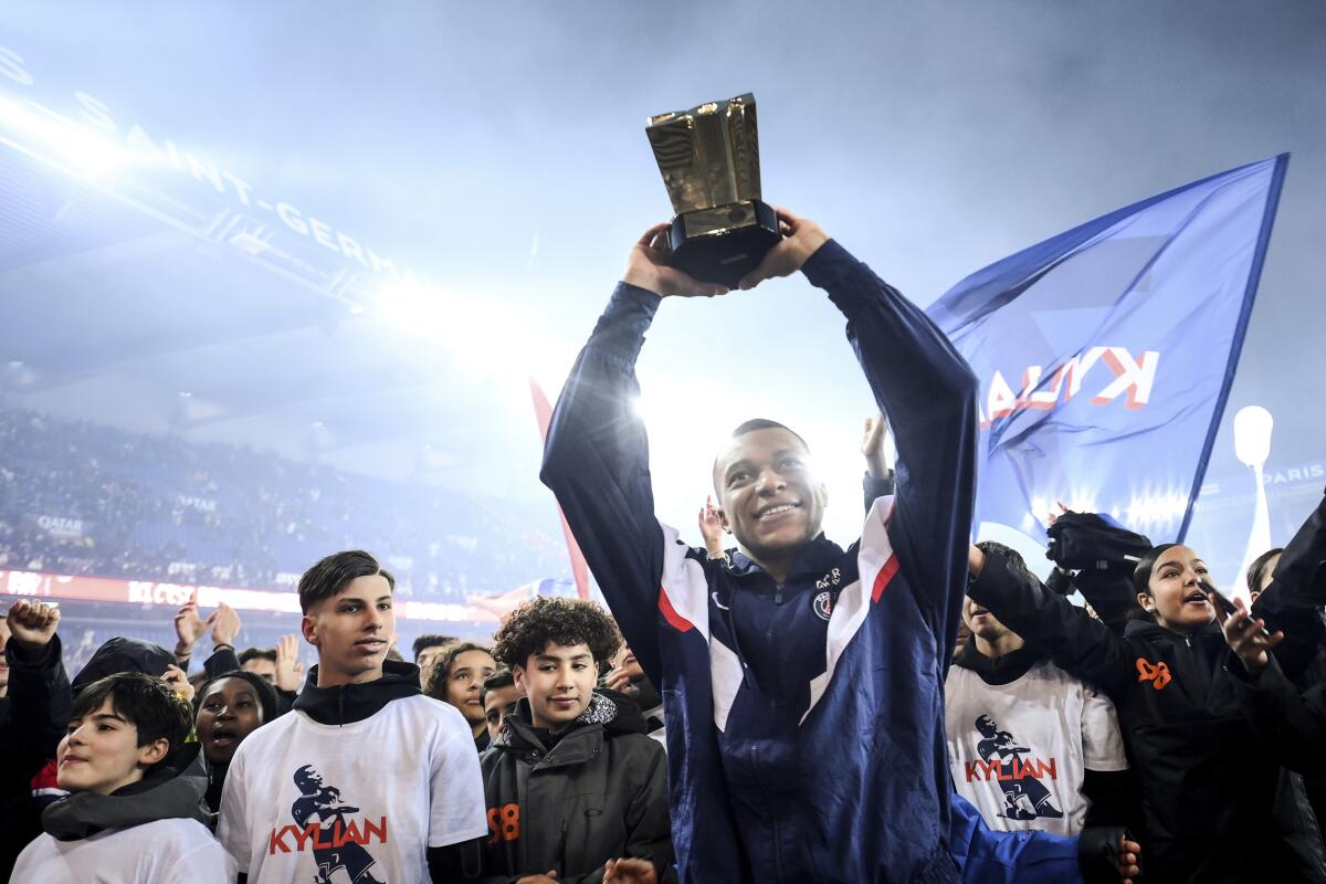 Kylian Mbappé, delantero del París Saint-Germain, alza el trofeo que lo acredita como máximo goleador 