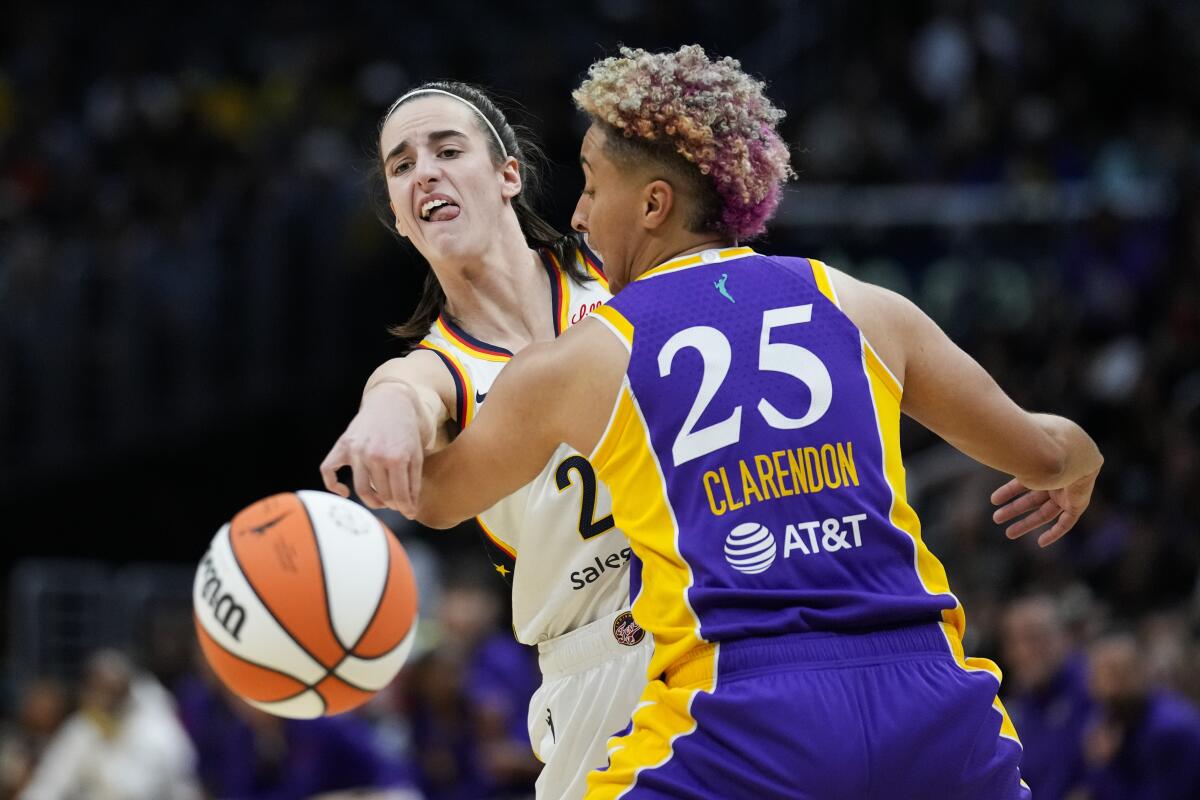 Indiana Fever guard Caitlin Clark, left, passes around Sparks guard Layshia Clarendon.