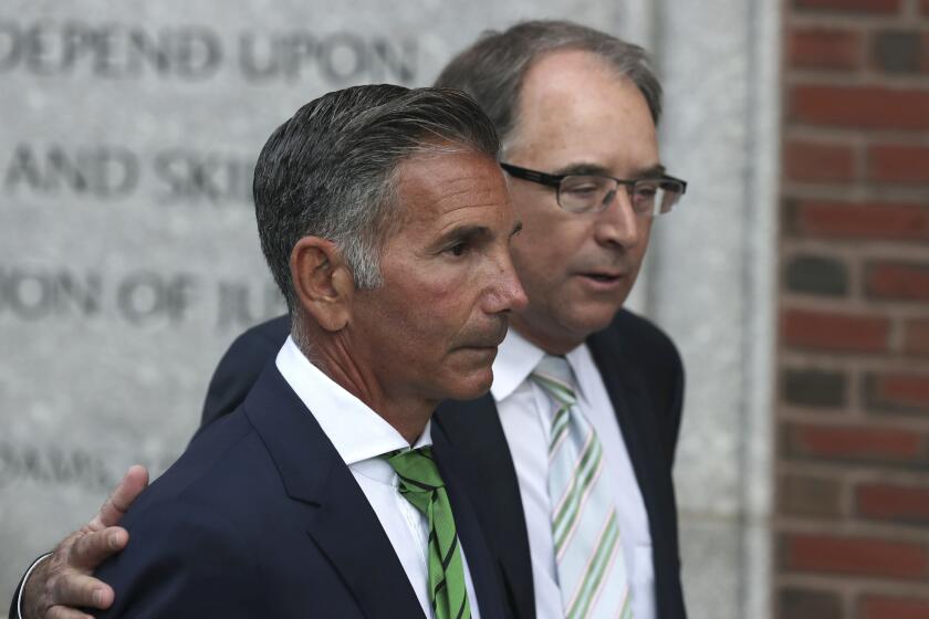 FILE - Clothing designer Mossimo Giannulli, foreground, departs federal court in Boston on Wednesday, April 3, 2019, after facing charges in a nationwide college admissions bribery scandal. Giannulli is asking to serve the remainder of his five-month prison term at home, saying he spent eight weeks in solitary confinement before being transferred to a minimum security camp this week. Giannulli's lawyers said Thursday, Jan. 14, 2021 that Giannulli believed he would only be held in quarantine for a short time before testing negative for the coronavirus. (AP Photo/Charles Krupa, File)