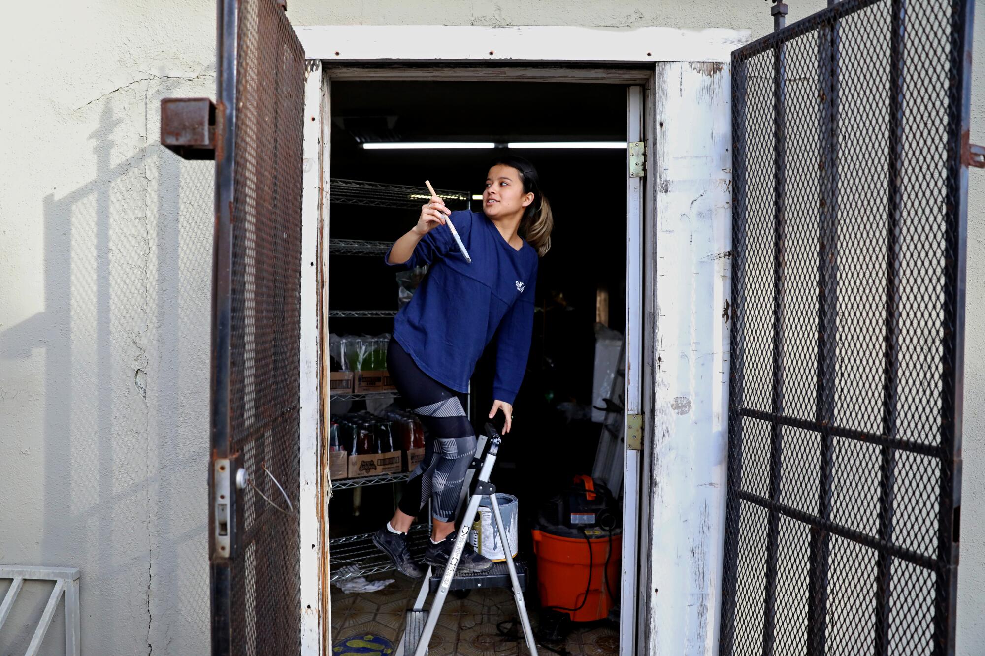 Hailey Cisneros helps her grandparents paint the walls of their flood-damaged El Gallito Bakery in Planada, Calif.