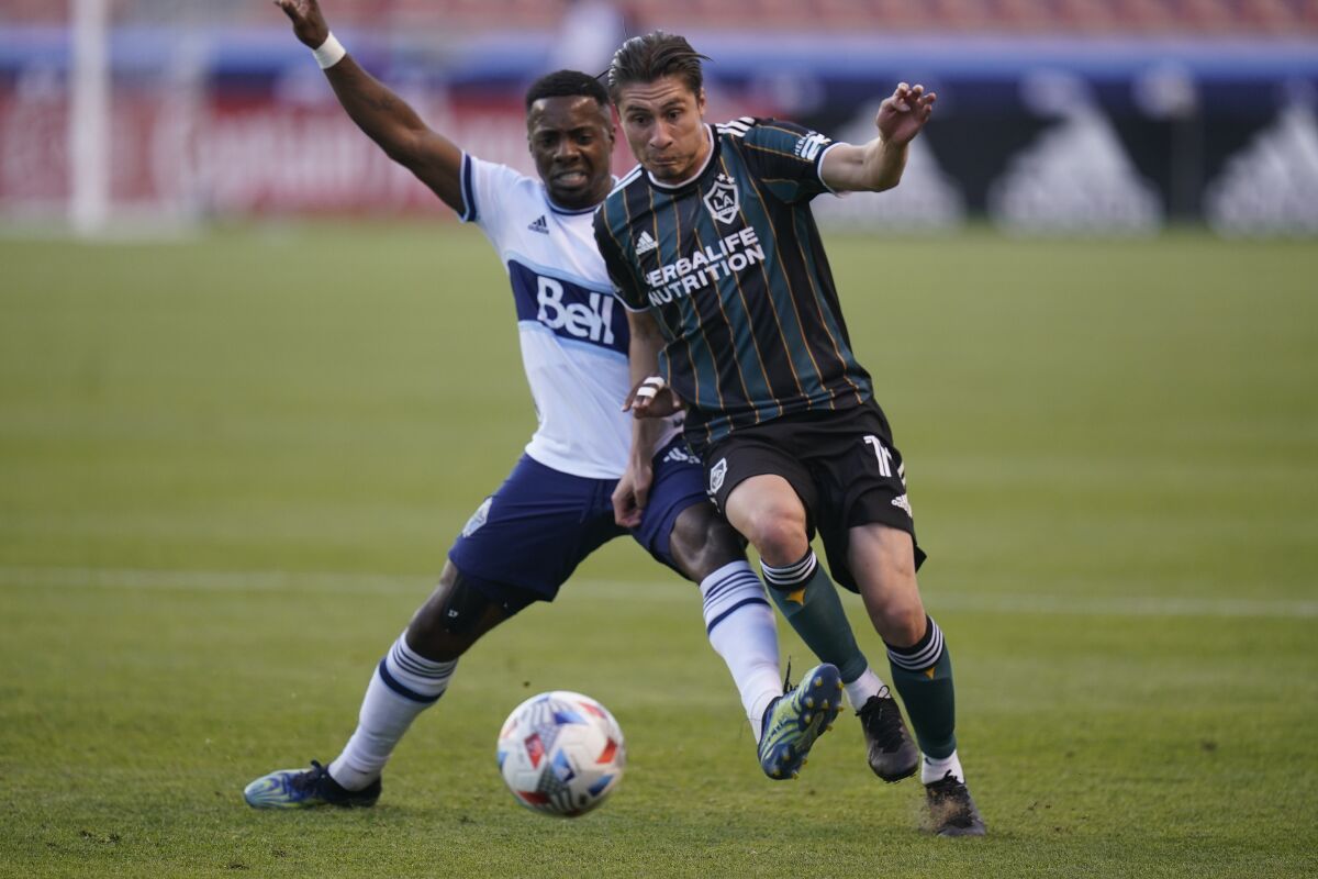 Whitecaps forward Cristian Dajome, left, battles Galaxy defender Jorge Villafana during the first half Saturday night.